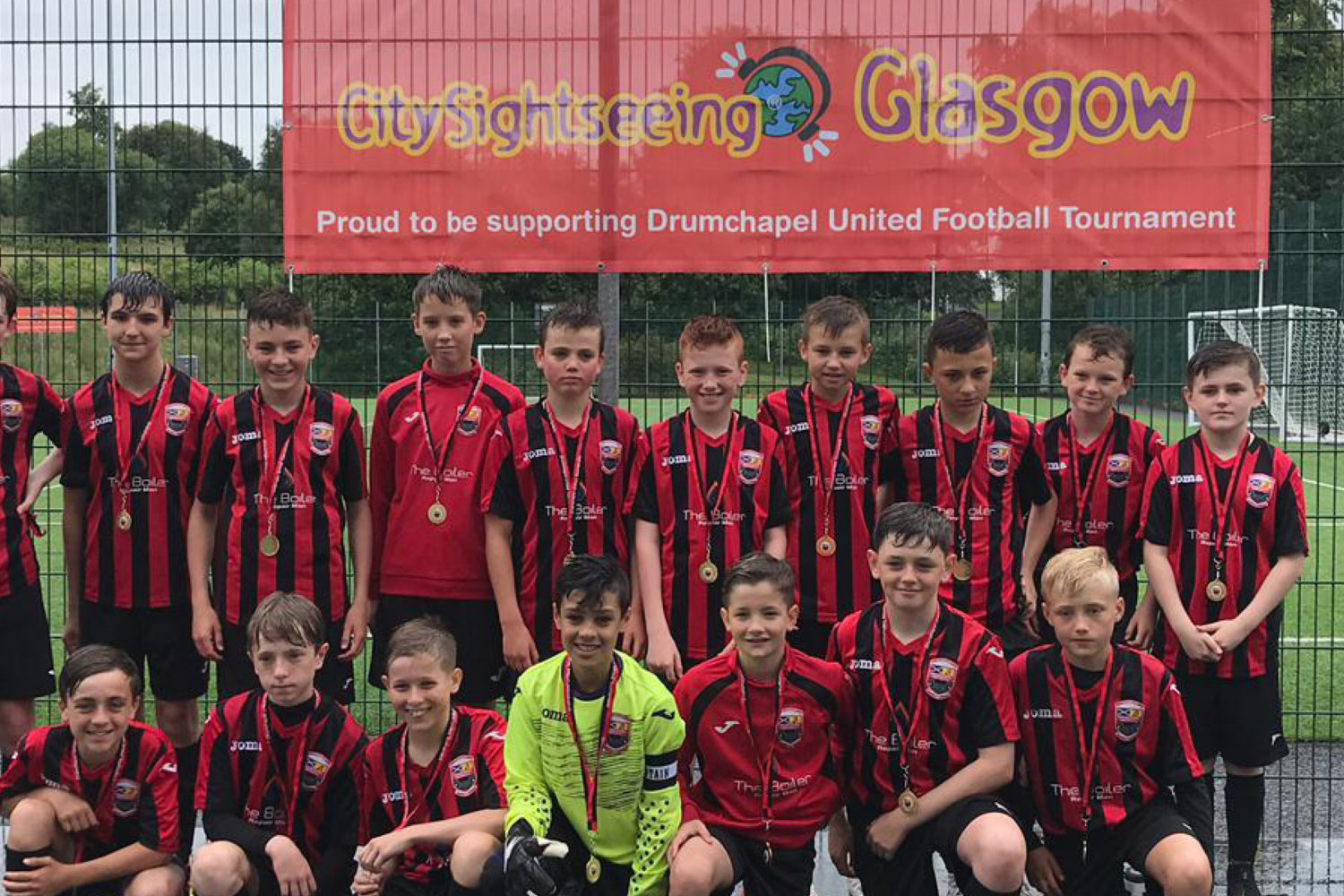 young boys football team huddle together in front of red city sightseeing banner