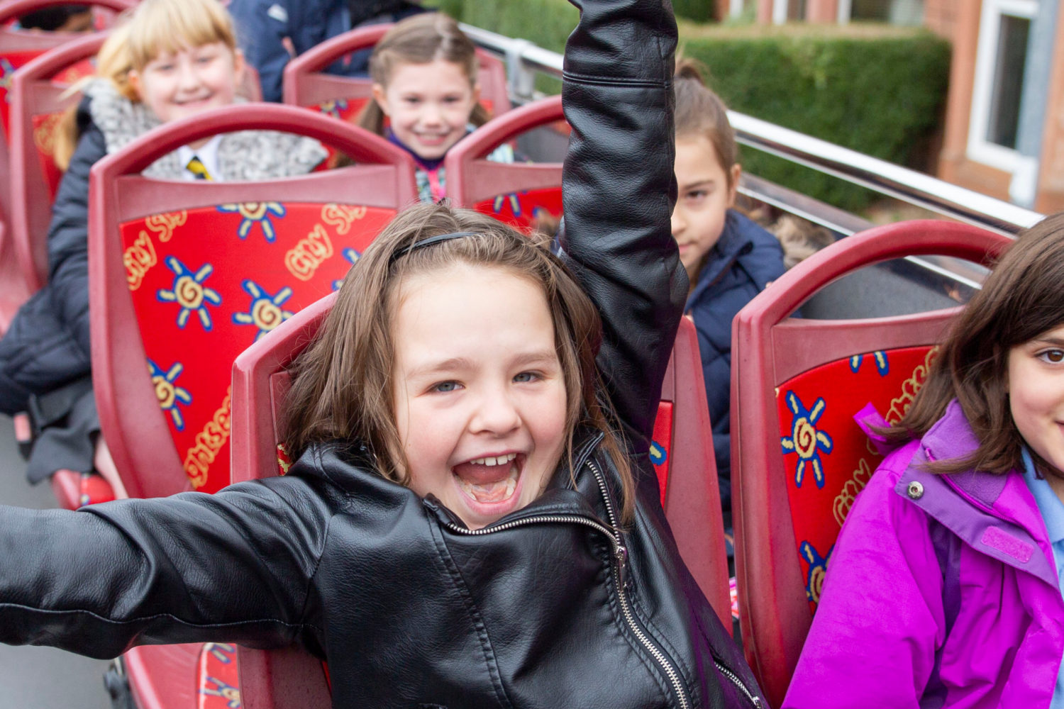 two girls smile on open top bus